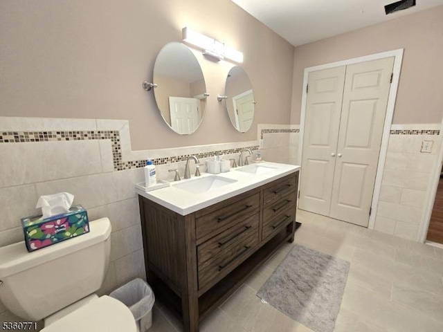 14 Constitution Ave, Roxbury Twp, NJ 07876 - bathroom featuring tile walls, toilet, double vanity, a wainscoted wall, and tile patterned flooring