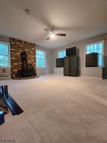 103 Mountain Top Rd, Lebanon Twp, NJ 08826 - unfurnished living room featuring a wood stove, carpet flooring, ceiling fan, baseboards, and a baseboard radiator