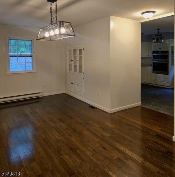 103 Mountain Top Rd, Lebanon Twp, NJ 08826 - unfurnished dining area with a baseboard radiator, dark wood-type flooring, baseboards, and a chandelier