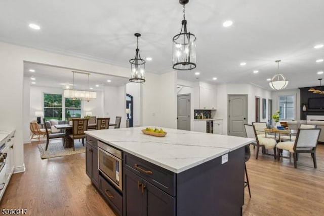48 Lewis Ave, Summit City, NJ 07901 - kitchen featuring stainless steel microwave, white cabinets, a kitchen island, recessed lighting, and light stone counters