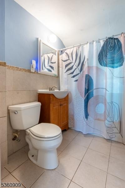 230 Lafayette Pl Unit 2B, Englewood City, NJ 07631 - bathroom featuring vanity, toilet, tile walls, tile patterned flooring, and a shower with curtain