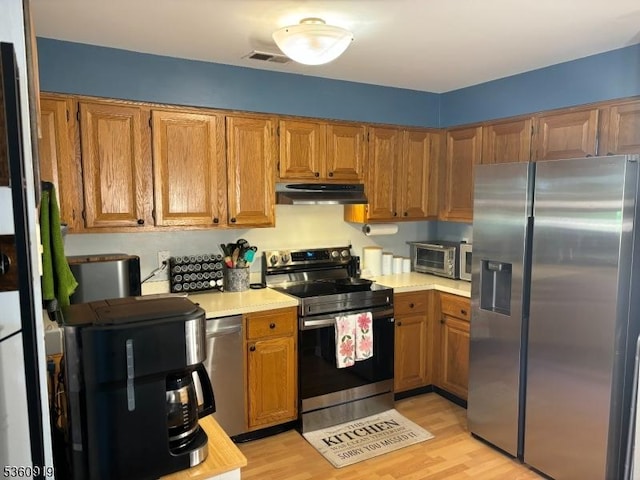 39 Augusta Dr, Clinton Twp, NJ 08801 - kitchen with stainless steel appliances, under cabinet range hood, light countertops, and brown cabinetry
