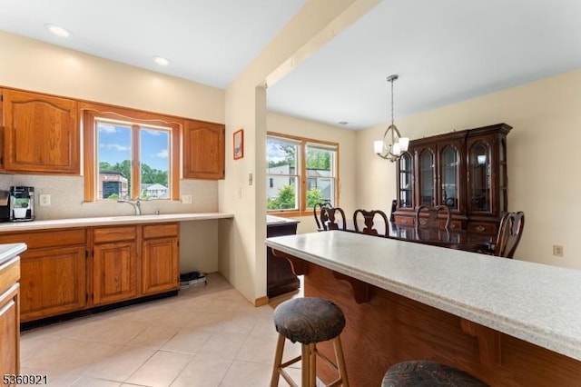 10 Garden Pl, Cranford Twp, NJ 07016 - kitchen with a kitchen bar, light countertops, a chandelier, and brown cabinetry