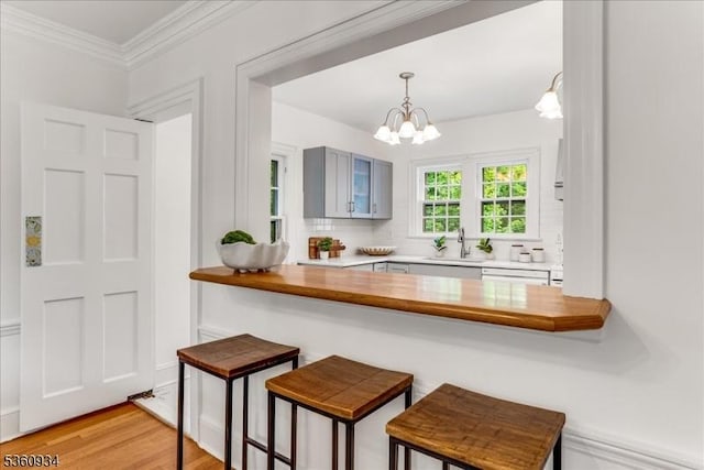 168 Grove St, Montclair Twp, NJ 07042 - kitchen with a sink, tasteful backsplash, a chandelier, a breakfast bar, and ornamental molding