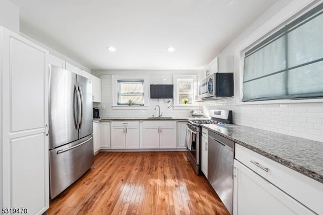 770 Stone St, Rahway City, NJ 07065 - kitchen with stainless steel appliances, a sink, tasteful backsplash, light wood-type flooring, and white cabinetry