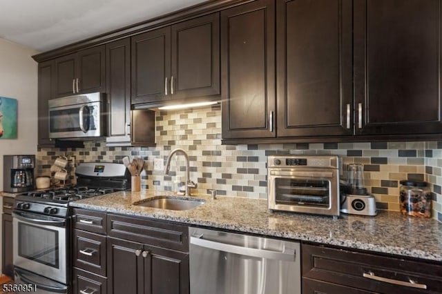 55 Jefferson St, Clifton City, NJ 07014 - kitchen featuring stainless steel appliances, a sink, backsplash, dark brown cabinetry, and light stone countertops