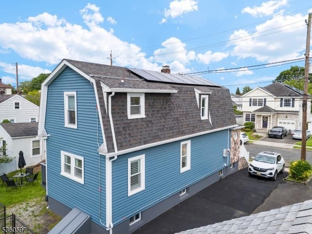 24-09 Raphael St, Fair Lawn Boro, NJ 07410 - view of side of home featuring roof with shingles, solar panels, a chimney, a gambrel roof, and a residential view