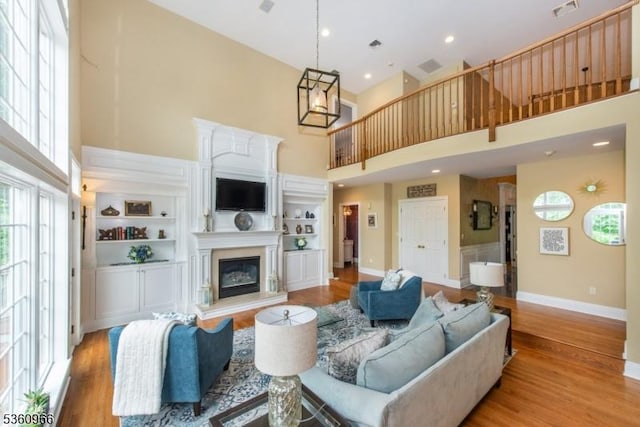 7 Briscoe Chase, Ringwood Boro, NJ 07456 - living room with a towering ceiling, a glass covered fireplace, baseboards, light wood finished floors, and built in shelves