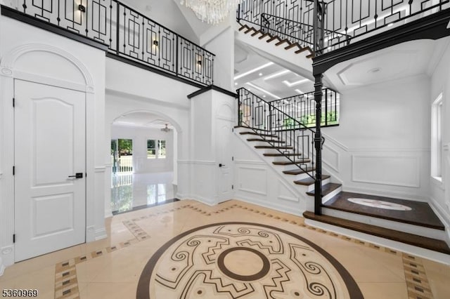 47 Cutlass Rd, Kinnelon Boro, NJ 07405 - foyer featuring inlaid floor details, a high ceiling, arched walkways, stairs, and a decorative wall