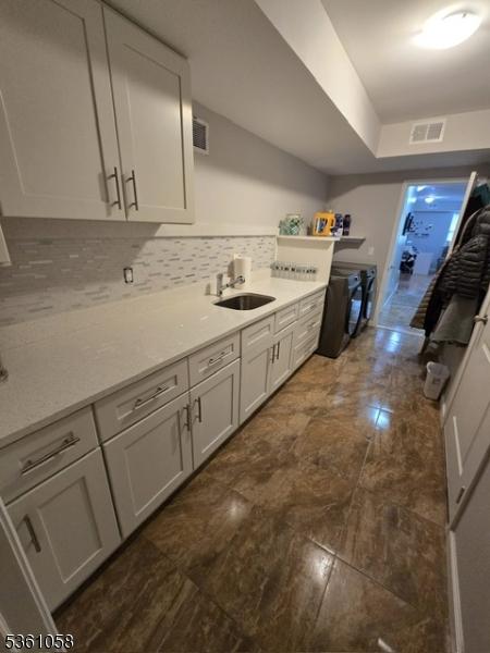 648 Marshall St, Elizabeth City, NJ 07206 - kitchen with a sink, backsplash, light countertops, and white cabinetry