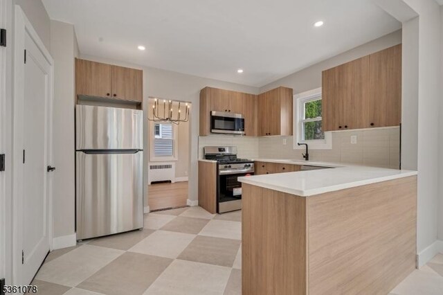 1535 Leslie St, Hillside Twp, NJ 07205 - kitchen featuring stainless steel appliances, radiator heating unit, a sink, a peninsula, and tasteful backsplash