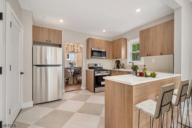 1535 Leslie St, Hillside Twp, NJ 07205 - kitchen with stainless steel appliances, a peninsula, a breakfast bar, backsplash, and a sink