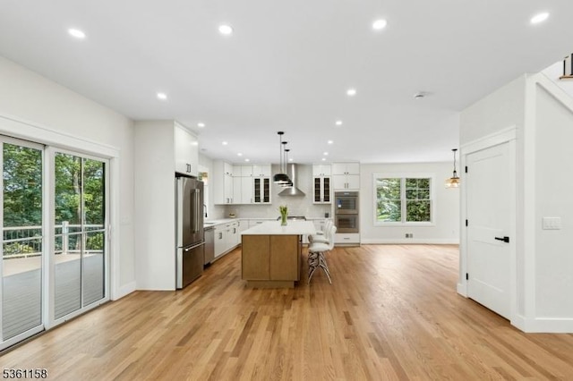 48 Hunterdon Blvd, Berkeley Heights Twp, NJ 07974 - kitchen featuring appliances with stainless steel finishes, light countertops, wall chimney range hood, white cabinets, and healthy amount of natural light