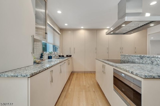 12 Fox Hollow Rd, Montville Twp, NJ 07045 - kitchen with wall chimney range hood, stainless steel microwave, light wood-type flooring, black electric stovetop, and light stone counters