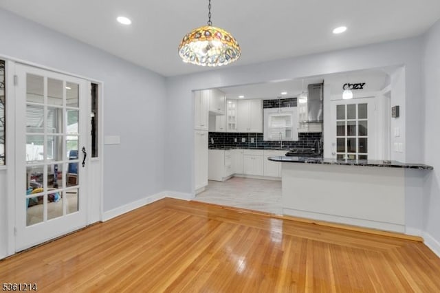 53 Elliot Pl, East Orange City, NJ 07018 - kitchen with dark countertops, wall chimney exhaust hood, white cabinets, baseboards, and backsplash