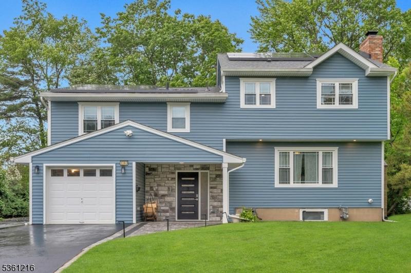 2283 Old Farm Rd, Scotch Plains Twp, NJ 07076 - view of front of property with roof mounted solar panels, a front lawn, a chimney, driveway, and a garage