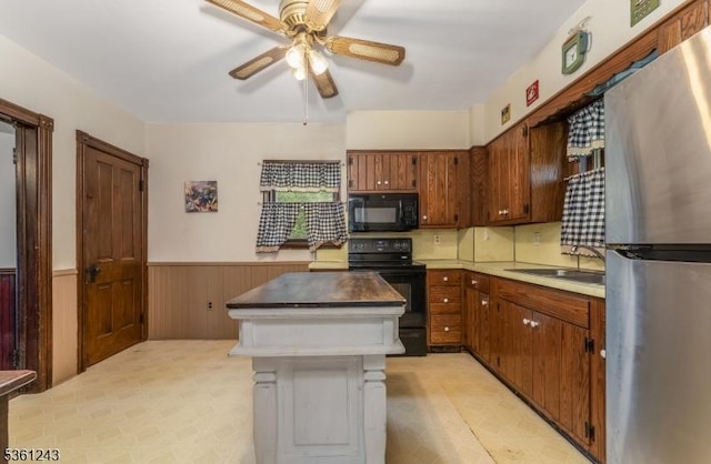 126 Park Ave, Lopatcong Twp, NJ 08865 - kitchen with black appliances, a sink, a wainscoted wall, a ceiling fan, and a kitchen island