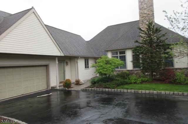 7 Troon Dr, Fredon Twp, NJ 07860 - view of front of property with an attached garage, asphalt driveway, a chimney, and a shingled roof