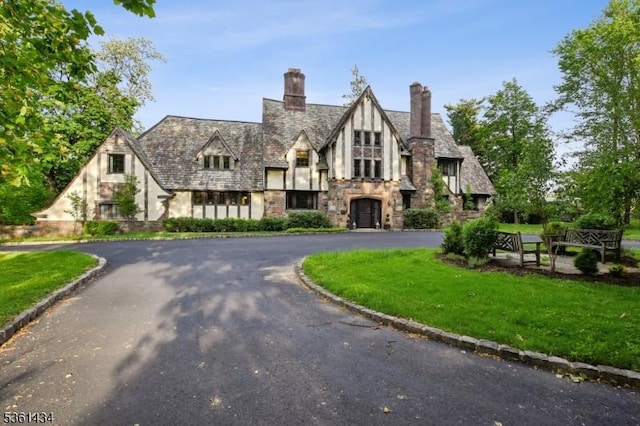 100 Gregory Ave, West Orange Twp, NJ 07052 - tudor home with stone siding, curved driveway, a front yard, and stucco siding