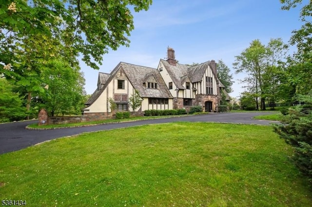 100 Gregory Ave, West Orange Twp, NJ 07052 - tudor home with stone siding, stucco siding, a front lawn, driveway, and a chimney