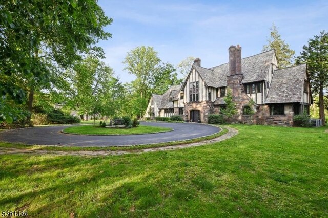 100 Gregory Ave, West Orange Twp, NJ 07052 - view of front facade featuring stone siding, curved driveway, a front yard, and a chimney