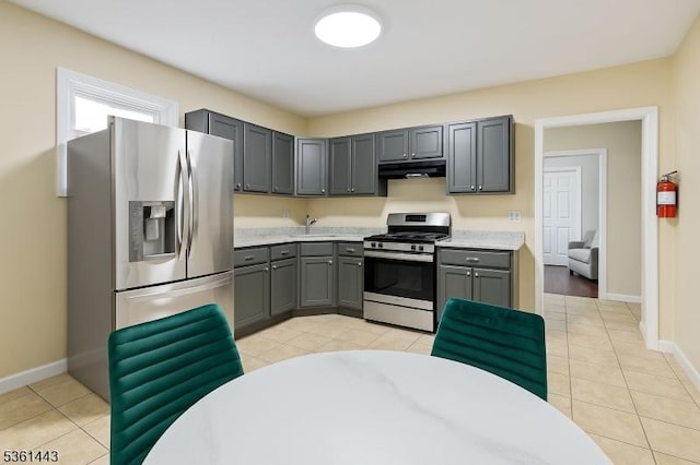 276 5th Ave, Paterson City, NJ 07524 - kitchen with stainless steel appliances, under cabinet range hood, gray cabinets, light tile patterned flooring, and baseboards