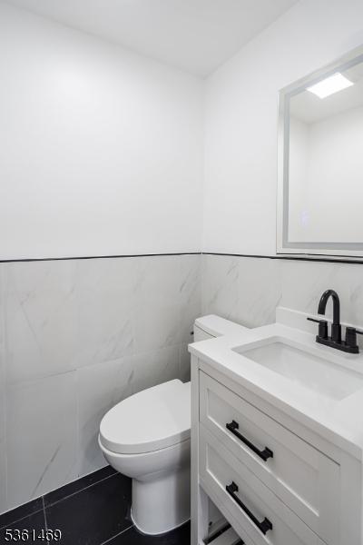 16 Deanna Dr Unit 23, Hillsborough Twp, NJ 08844 - bathroom with tile walls, vanity, toilet, and a wainscoted wall
