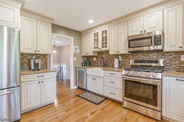 1730 Arrowbrook Dr, Bridgewater Twp, NJ 08836 - kitchen featuring appliances with stainless steel finishes, decorative backsplash, light wood finished floors, glass insert cabinets, and light stone countertops