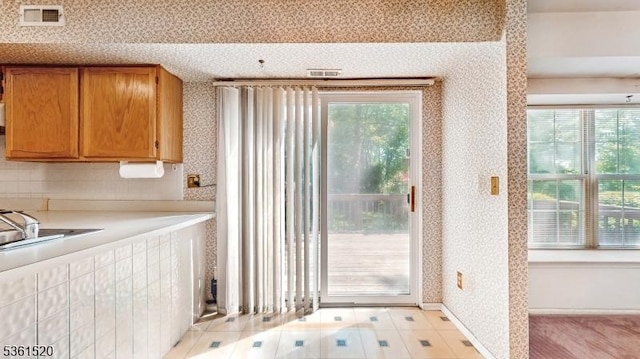 301 Smithwold Rd, Franklin Twp, NJ 08873 - kitchen featuring wallpapered walls, light countertops, plenty of natural light, brown cabinetry, and baseboards
