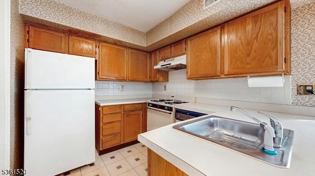 301 Smithwold Rd, Franklin Twp, NJ 08873 - kitchen with white appliances, under cabinet range hood, a sink, wallpapered walls, and brown cabinets