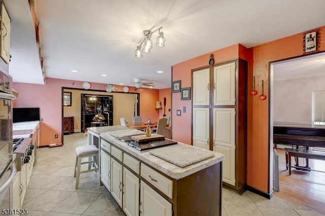 933 River Rd, Hillsborough Twp, NJ 08844 - kitchen featuring a kitchen island, light countertops, gas stovetop, light tile patterned floors, and a ceiling fan