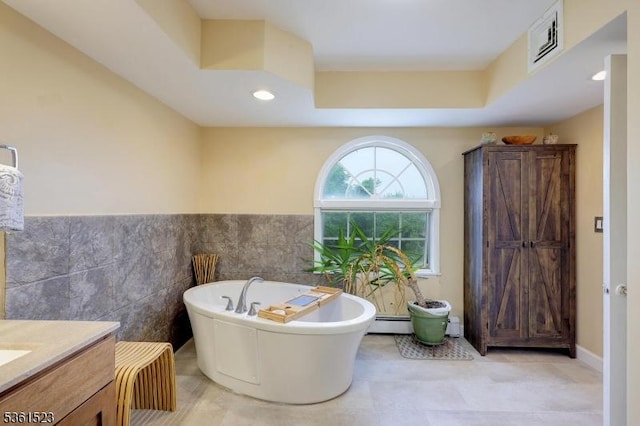 933 River Rd, Hillsborough Twp, NJ 08844 - bathroom with tile walls, a freestanding bath, a baseboard heating unit, vanity, and a wainscoted wall