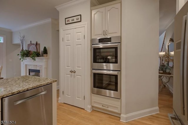 302 Lindabury Ln, Tewksbury Twp, NJ 07979 - kitchen with appliances with stainless steel finishes, ornamental molding, light wood-style floors, light stone counters, and a glass covered fireplace