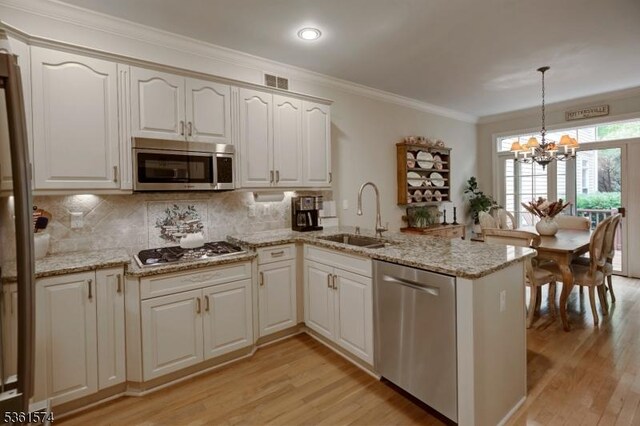 302 Lindabury Ln, Tewksbury Twp, NJ 07979 - kitchen featuring appliances with stainless steel finishes, a peninsula, a chandelier, light wood-type flooring, and ornamental molding
