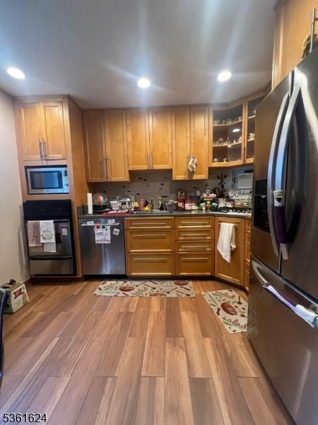 37 Manchester Ct Unit 121, Wayne Twp, NJ 07470 - kitchen featuring appliances with stainless steel finishes, dark countertops, light wood finished floors, recessed lighting, and glass insert cabinets