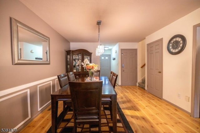 17 Iron Forge Vlg S, Pompton Lakes Boro, NJ 07442 - dining space with light wood-style floors, stairs, a wainscoted wall, and a chandelier
