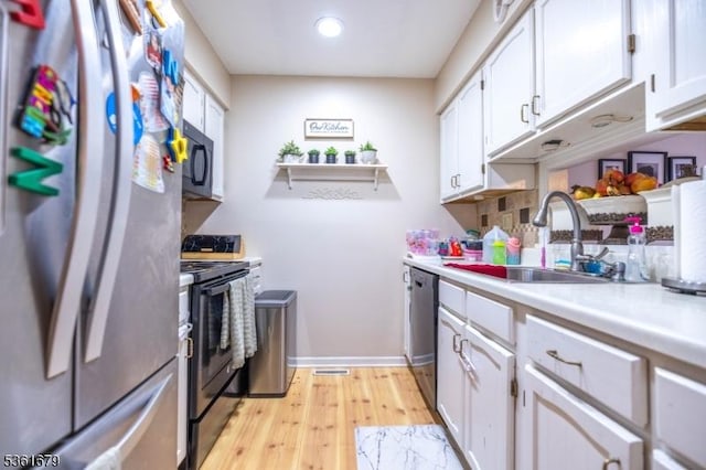17 Iron Forge Vlg S, Pompton Lakes Boro, NJ 07442 - kitchen with black appliances, a sink, light countertops, white cabinets, and light wood-style floors