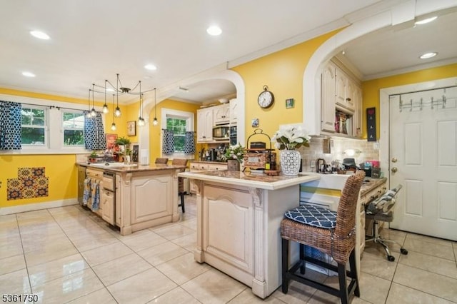 27 Fairway Dr, West Orange Twp, NJ 07052 - kitchen with a peninsula, crown molding, stainless steel microwave, arched walkways, and light tile patterned floors