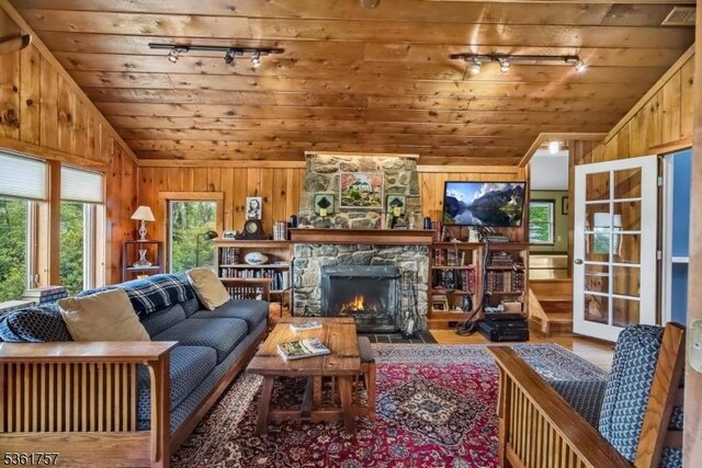 172 Alpine Trl, Sparta Twp, NJ 07871 - living room featuring vaulted ceiling, wooden ceiling, wood finished floors, wooden walls, and a stone fireplace