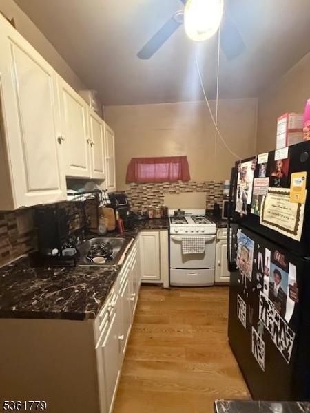 286 N 6th St, Prospect Park Boro, NJ 07508 - kitchen featuring white gas stove, freestanding refrigerator, white cabinets, and tasteful backsplash