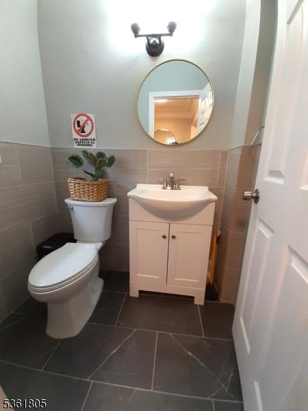 336 E 41st St, Paterson City, NJ 07504 - bathroom featuring tile walls, vanity, toilet, wainscoting, and tile patterned floors