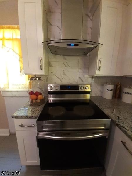 336 E 41st St, Paterson City, NJ 07504 - kitchen with electric stove, range hood, white cabinets, tasteful backsplash, and light stone countertops