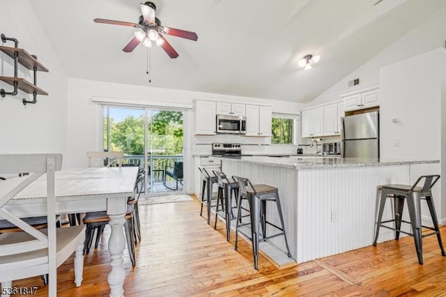 80 Cedar Tree Dr, Vernon Twp, NJ 07422 - kitchen with stainless steel appliances, lofted ceiling, a breakfast bar area, ceiling fan, and white cabinetry