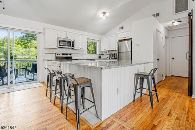 80 Cedar Tree Dr, Vernon Twp, NJ 07422 - kitchen with stainless steel appliances, a sink, a breakfast bar, white cabinetry, and vaulted ceiling