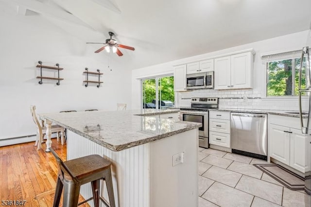 80 Cedar Tree Dr, Vernon Twp, NJ 07422 - kitchen featuring appliances with stainless steel finishes, ceiling fan, decorative backsplash, a breakfast bar area, and white cabinetry