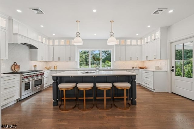 107 Rutland Rd, Glen Rock Boro, NJ 07452 - kitchen with range with two ovens, a center island with sink, tasteful backsplash, a breakfast bar area, and light countertops