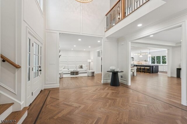 107 Rutland Rd, Glen Rock Boro, NJ 07452 - entrance foyer with stairway, a high ceiling, a chandelier, a decorative wall, and crown molding