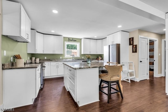 172 Ferry Rd, Delaware Twp, NJ 08822 - kitchen with a kitchen breakfast bar, dark stone counters, dark wood-style flooring, a kitchen island, and white cabinetry