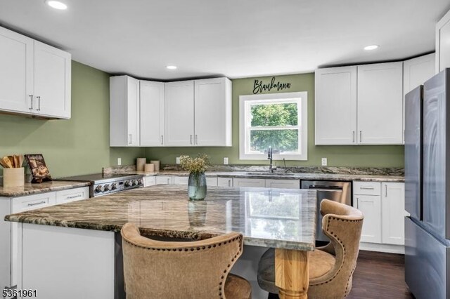 172 Ferry Rd, Delaware Twp, NJ 08822 - kitchen with freestanding refrigerator, stove, stone counters, a breakfast bar, and white cabinetry