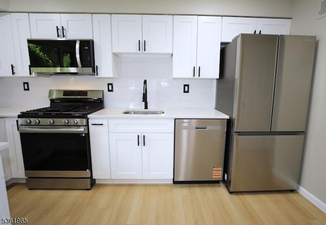914 Merritt Dr Unit E, Hillsborough Twp, NJ 08844 - kitchen featuring appliances with stainless steel finishes, a sink, light wood-style floors, white cabinets, and light countertops